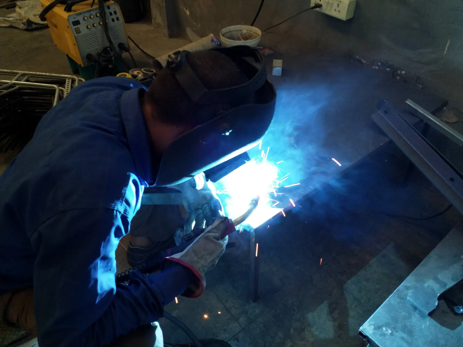 Welder MIG welding a steel frame in the Spline Curves workshop